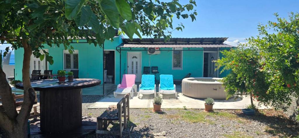 a blue house with three chairs and a tub at Olive Grove Retreat Podgorica in Vranj