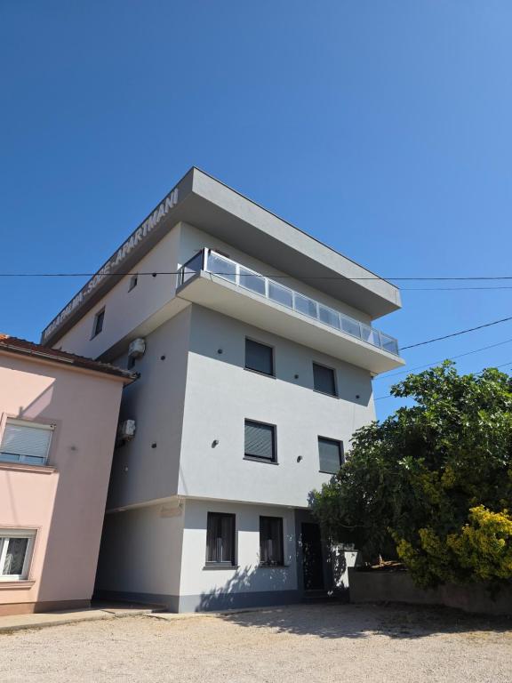 a white building with a tree in front of it at Villa Palma - With Free Parking in Mostar