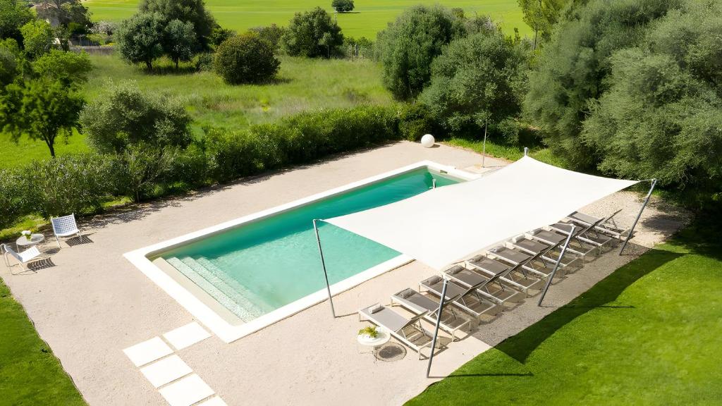 an overhead view of a swimming pool with a white umbrella and chairs at Can Soto in Palma de Mallorca