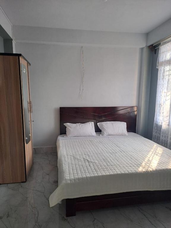 a bedroom with a large bed with a wooden headboard at Nashlem Homestay in Mawphlang