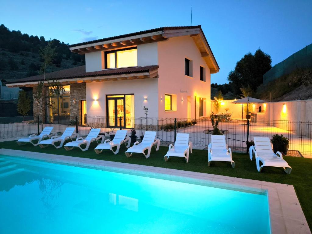 a villa with a swimming pool in front of a house at Casa La Huertona de Castroserna in Castroserna de Arriba