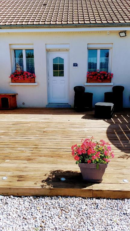 a wooden deck with a pot of flowers in front of a house at gite repos et tranquillité en baie de somme in Cayeux-sur-Mer