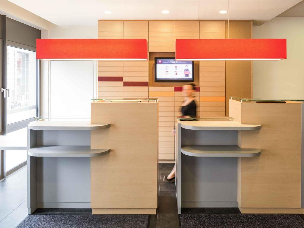 a woman is standing behind a counter in an office at ibis Esch Belval in Esch-sur-Alzette