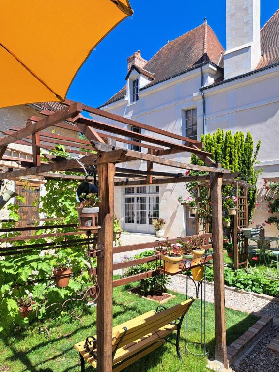 a garden with a bench and an umbrella at Chambres d'Hôtes L'Ecu in Preuilly-sur-Claise