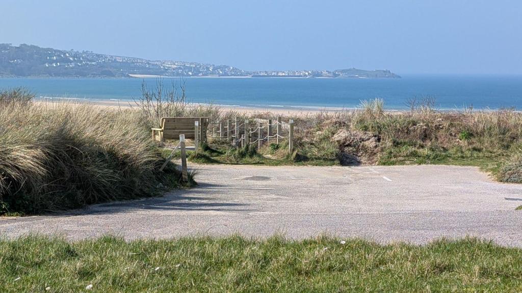 a bench on the side of a road near the ocean at C19 Old Range, Riviere Towans in Hayle