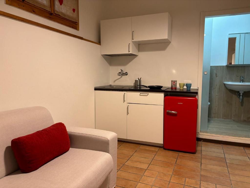 a living room with a couch and a red refrigerator at Monolocale Cerreto Laghi in Cerreto Laghi