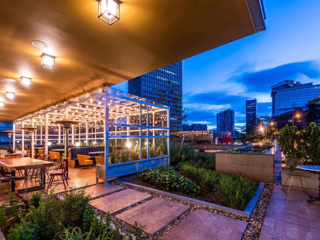 a rooftop patio with a view of a city at night at ibis Bogota Museo in Bogotá