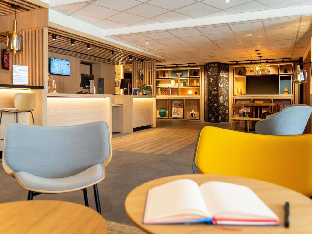 a library with a book on a table and chairs at ibis Loriol Le Pouzin in Le Pouzin