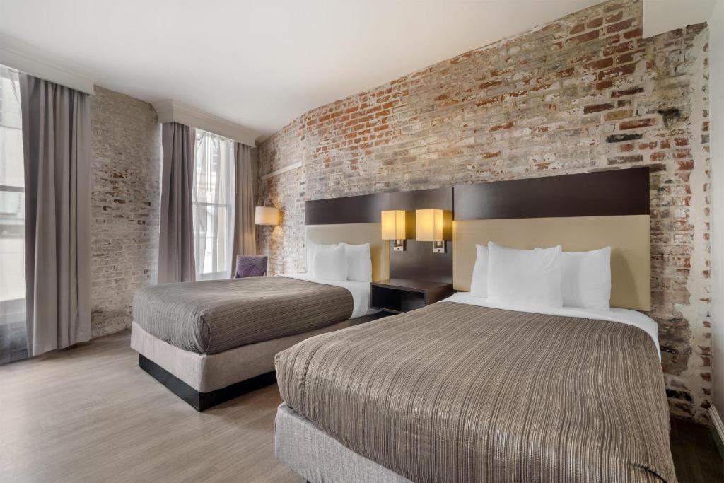 ein Hotelzimmer mit zwei Betten und einer Backsteinwand in der Unterkunft Best Western Plus St. Christopher Hotel in New Orleans