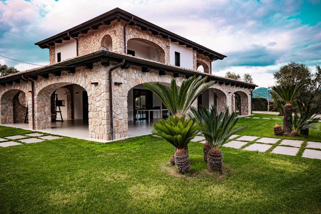 a stone house with palm trees in the yard at Lilium B&B Villa Patrizia - Con piscina e parcheggio by Mamo Florence in Itri