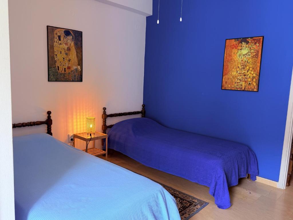a bedroom with two beds and a blue wall at Art & Motion Union - Guest Room 5 in Andros