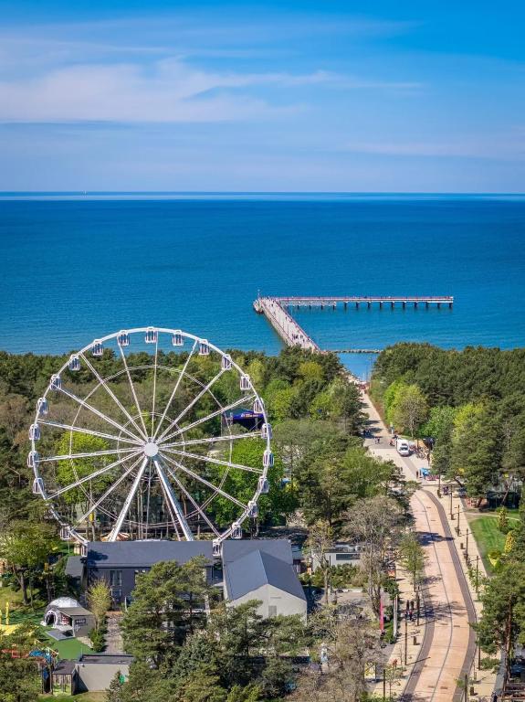 a ferris wheel next to the ocean with a pier at Melt in Palanga Self check-in in Palanga