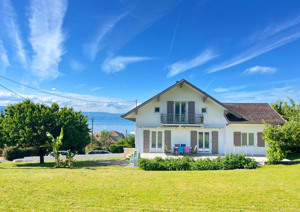 a white house with a balcony on a lawn at VILLA LÉMAN - Panoramic lake view in Évian-les-Bains