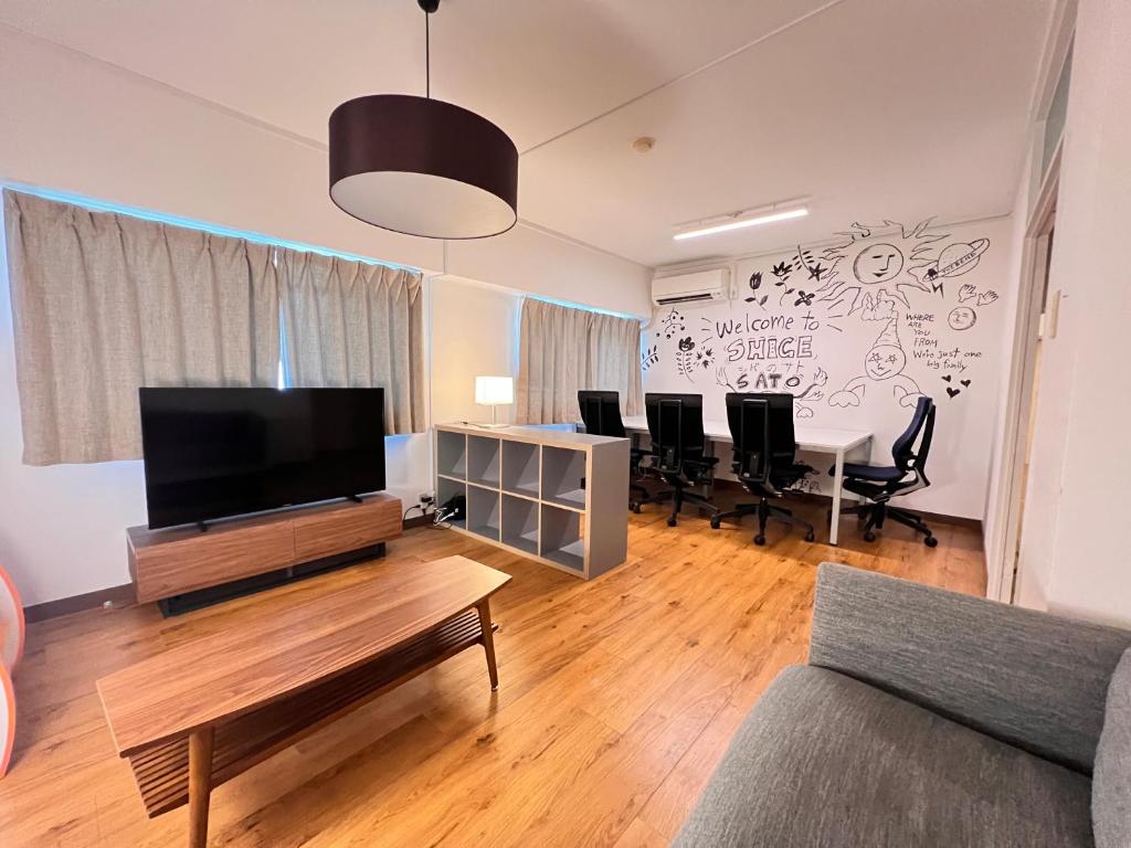 a living room with a tv and a table with chairs at 北浜703 3ベッドルーム貸切 高松港近く 最大6名 in Takamatsu