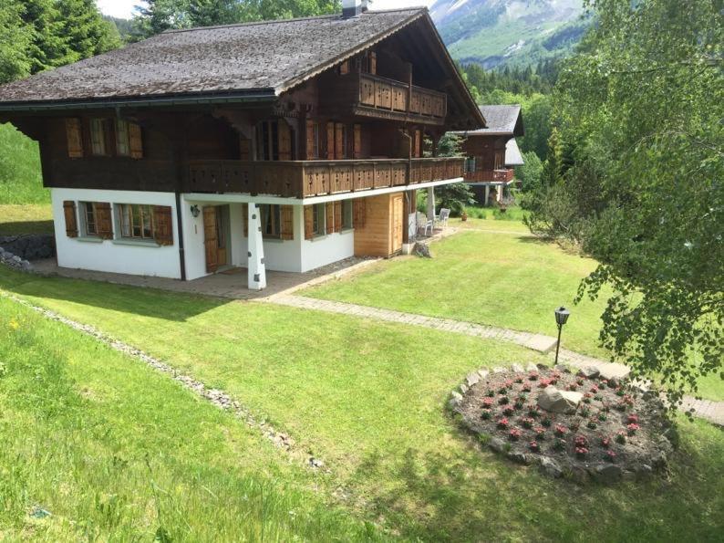 a large wooden house with a grassy yard in front of it at Chalet Castor in Les Diablerets