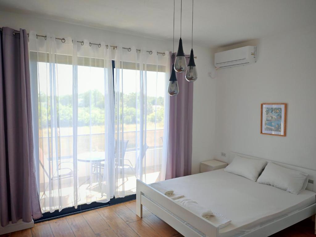 a bedroom with a bed and a balcony with a table at White apartments in Ulcinj