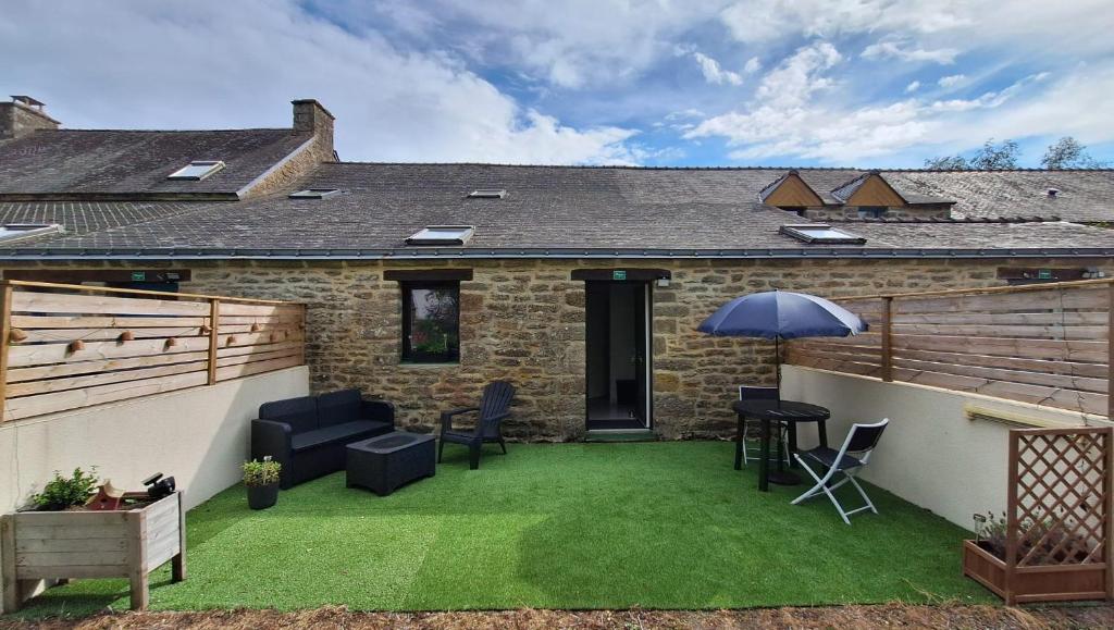 a patio with a lawn with chairs and an umbrella at Studio 09 in Sulniac