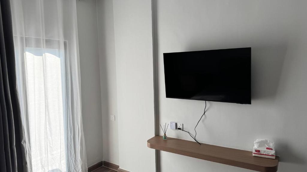 a flat screen tv hanging on a wall next to a window at Azure Suite Apartment - AOSIS in Bagam