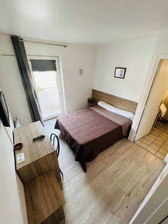 a small room with a bed and a table at Hôtel Au Bon coin chez Pierre in Franconville