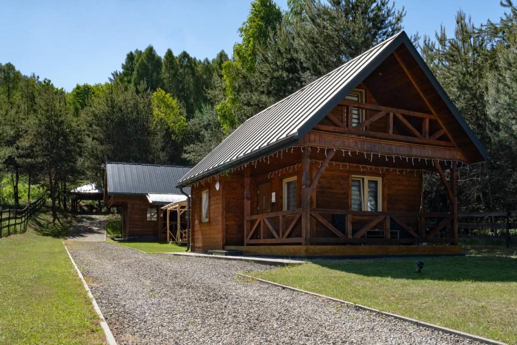 a log cabin with a gambrel roof and a gravel driveway at Domki całoroczne u Greściaków in AdamÃ³w