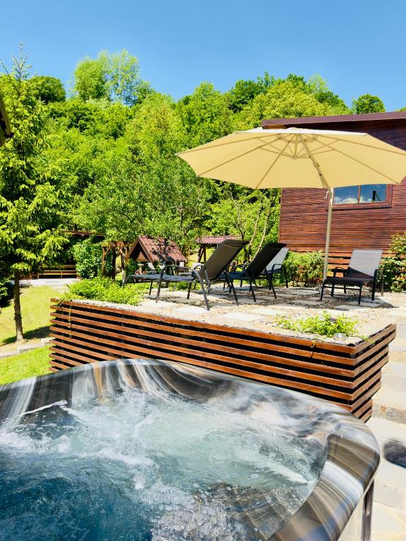 a hot tub with an umbrella in a yard at Casa Rogin in Buhalniţa