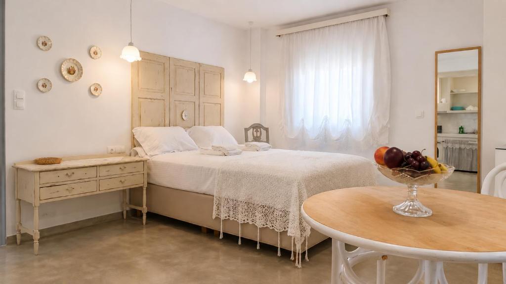 a white bedroom with a bed and a table at Est 1852 - Cozy in Andros