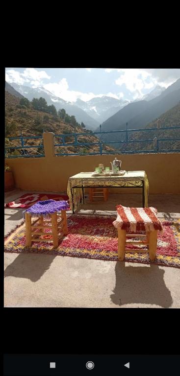a room with a table and two benches on a rug at Imlil agarssiwal in Aguersioual