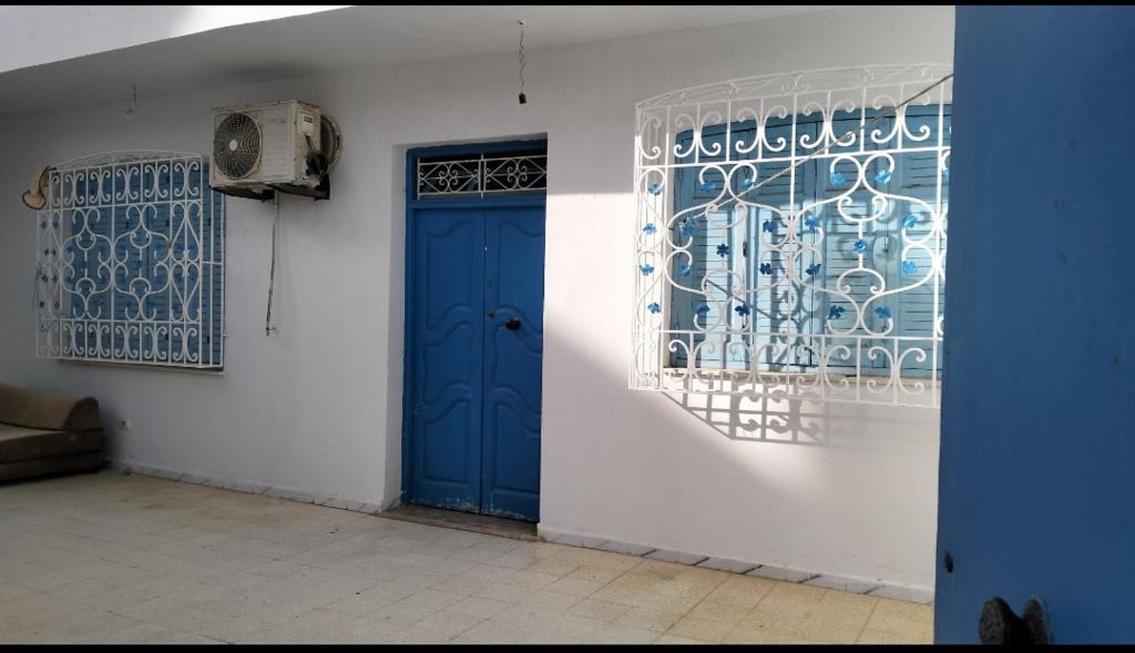 a blue door on a white wall with a window at Maison indépendante pieds dans l'eau in Sousse