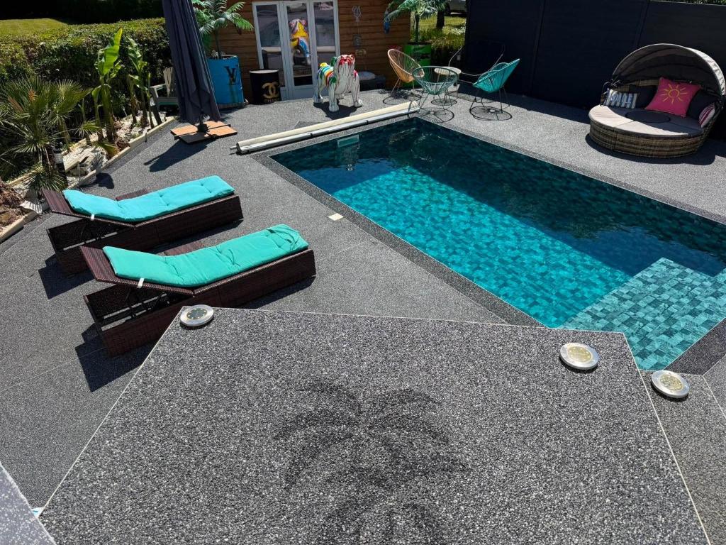a swimming pool with chairs and a palm tree next to it at Maison cocooning , avec double jacuzzi et piscine in La Machine