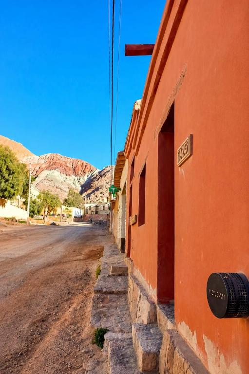 an empty street next to a building with mountains in the background at hospedaje chango luna in Purmamarca