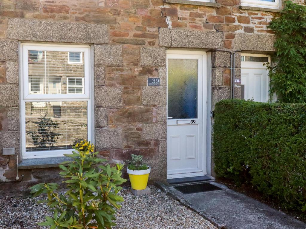 a brick house with a white door and two windows at Tin Lantern Cottage in Redruth