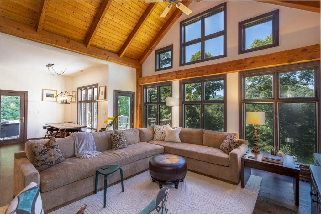 a living room with a large couch and windows at Evergreen Cottage in Blowing Rock