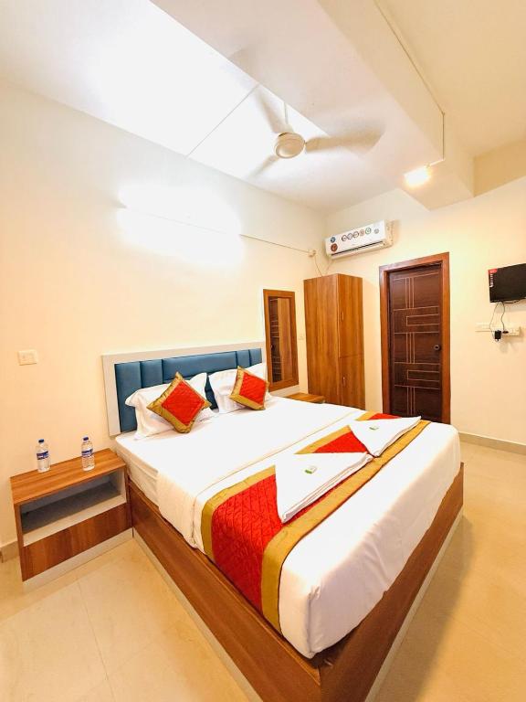 a bedroom with a large bed with red pillows at Hotel SAI GRAND in Mangalore