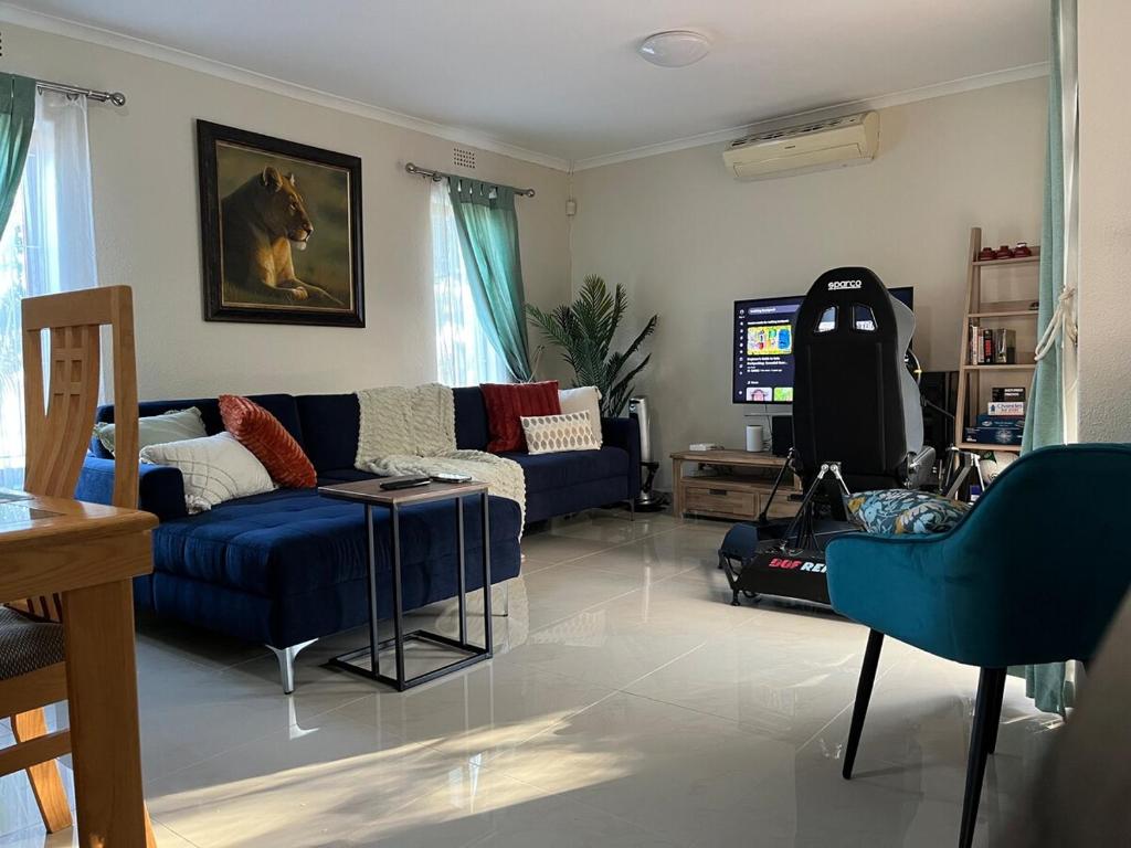 a living room with a blue couch and a tv at Indigo Nest in Edgemead