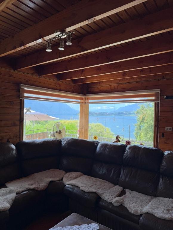 a black leather couch in a room with a large window at Casa Costanera in Panguipulli