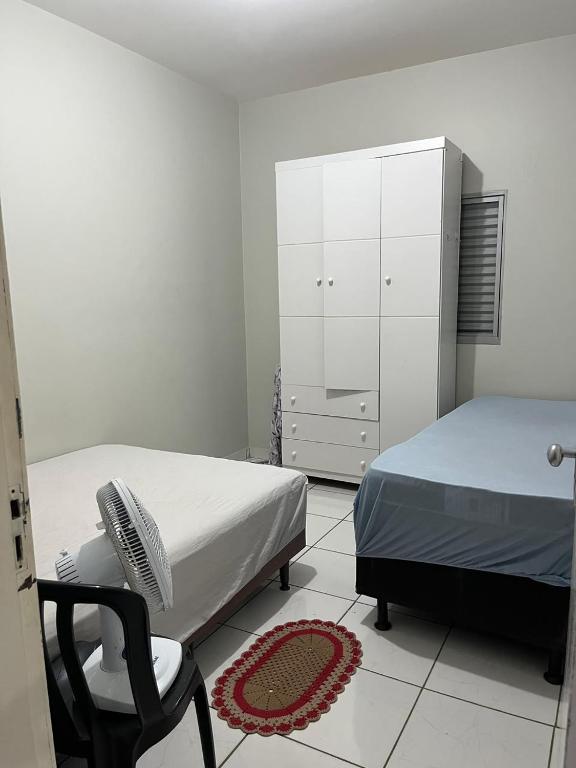 a bedroom with two beds and a chair and a dresser at Quarto individual Quarto 2 in Montes Claros