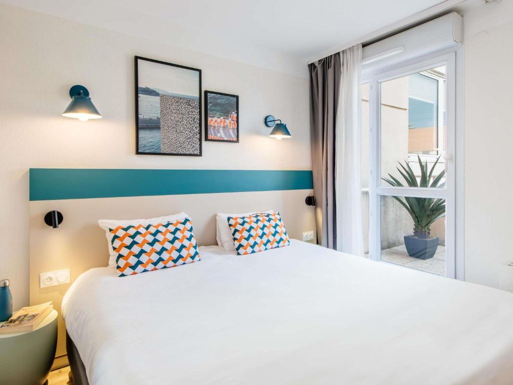 a bedroom with a white bed and a window at Aparthotel Adagio Access Marseille Prado Périer in Marseille
