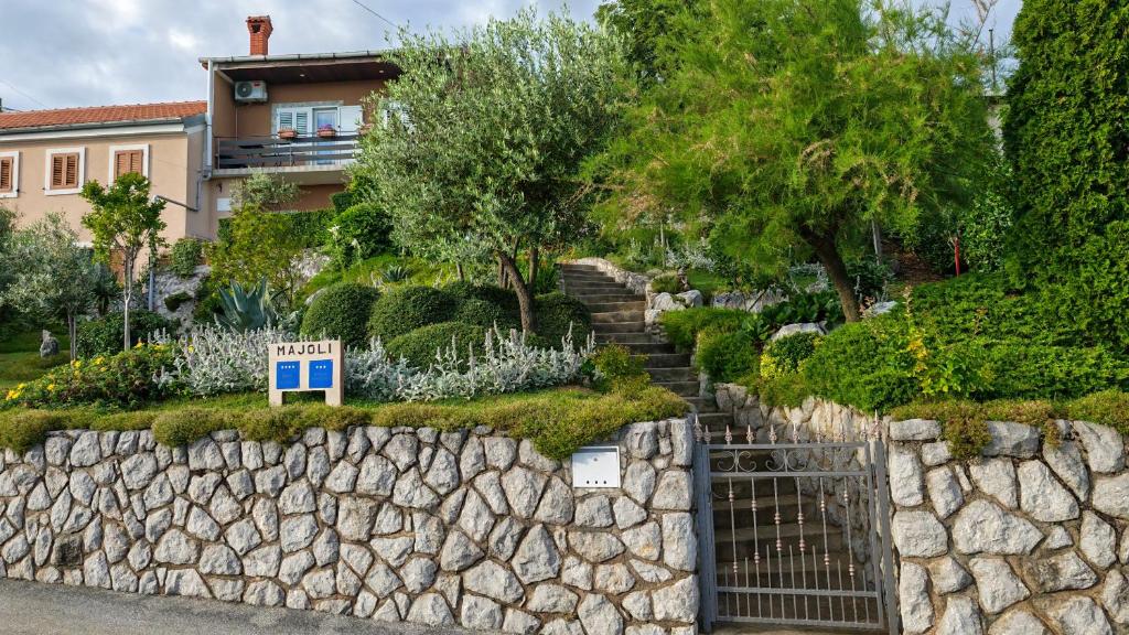 a stone wall with a gate in front of a house at Apartman i Studio apartman Majoli in Kukuljanovo