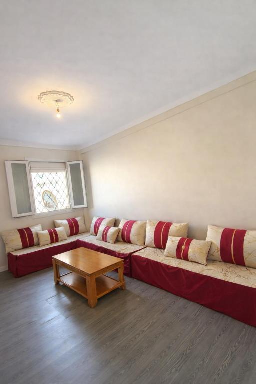 a living room with a red couch and a table at F3 SALAMANDRE à CORNICHE CASA MAZA in Mostaganem