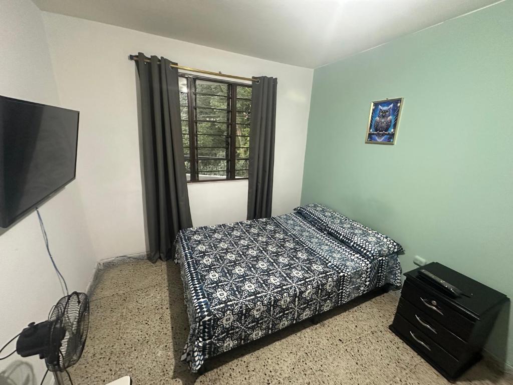 a bedroom with a bed and a tv and a window at Habita Coliving La Palma in Medellín