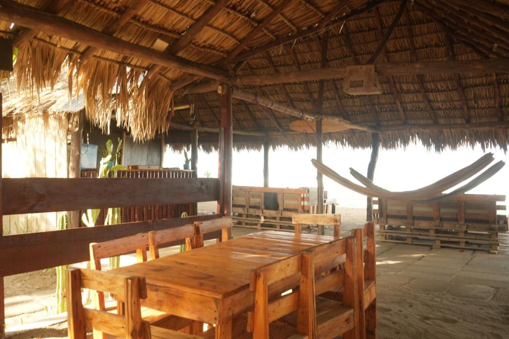 a wooden table and chairs in a straw hut at Mojo Surf House in Popoyo