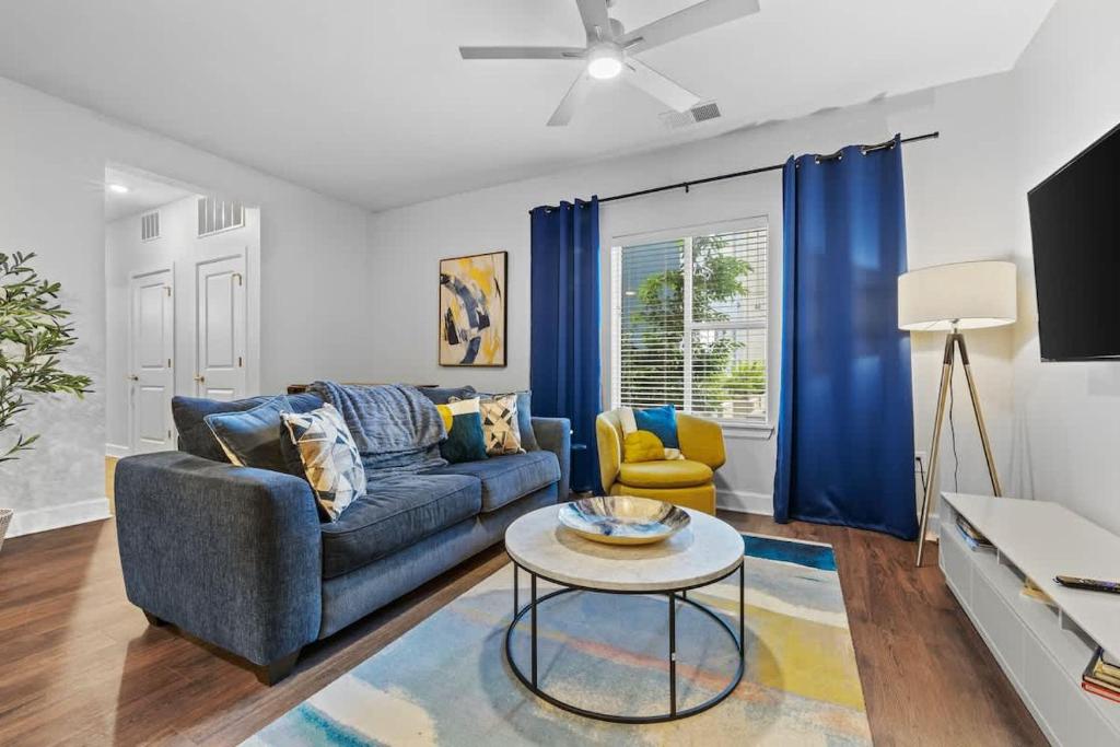 a living room with a blue couch and a table at Spacious 2BR N Gulch Walk to Broadway & Rooftops in Nashville