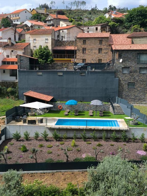 a swimming pool with umbrellas in a city at Casa Resineiro com Piscina, Garagem e Terraço in Proença-a-Nova