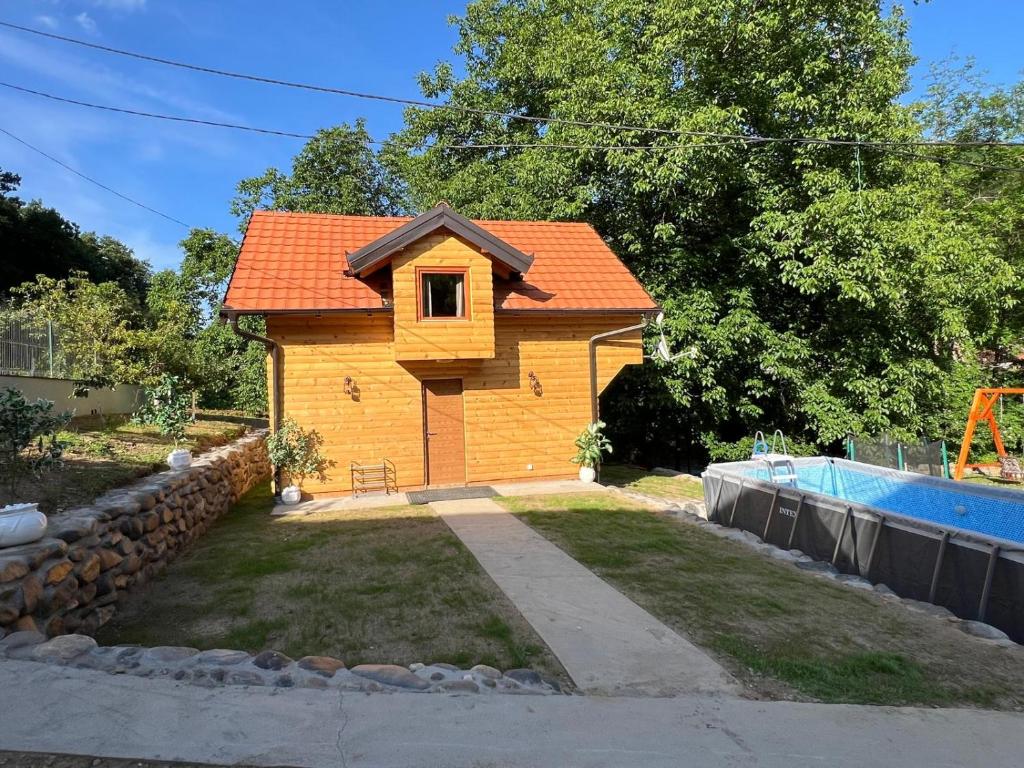 a small house with an orange roof next to a pool at Brvnarica na reci in Brus