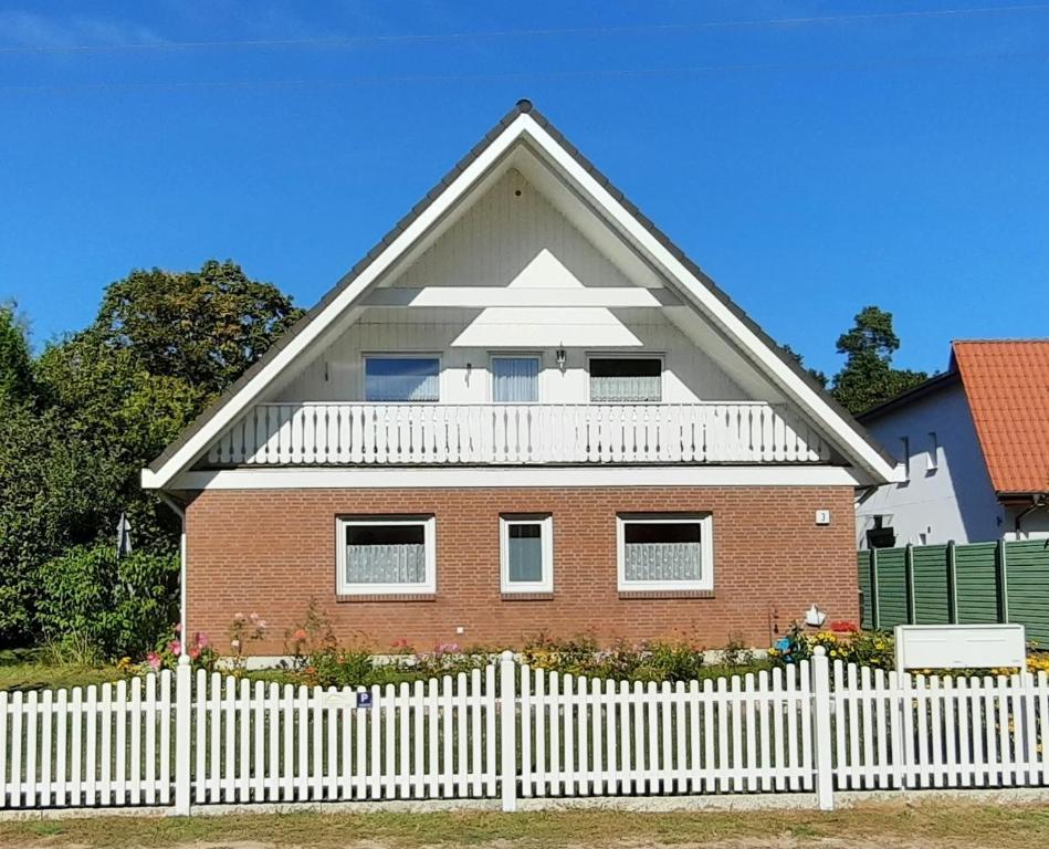 a red brick house with a white picket fence at Ferienwohnung Bandow in Woltersdorf