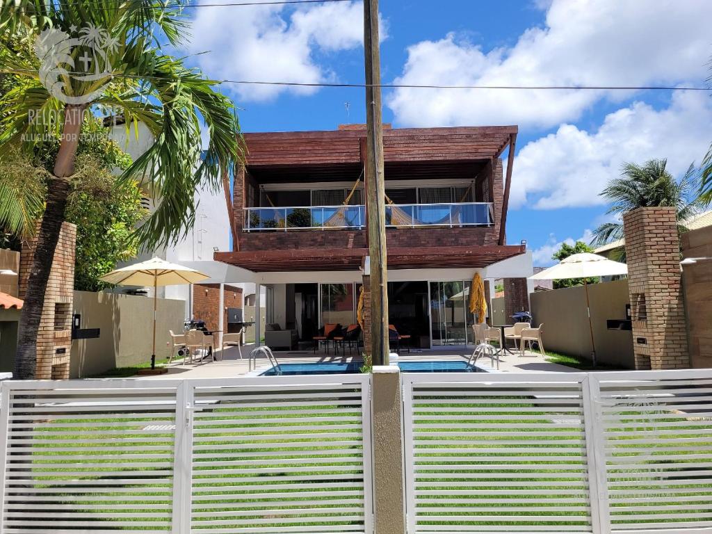 a house with a white fence and a swimming pool at Vila Sol Serrambi in Porto De Galinhas