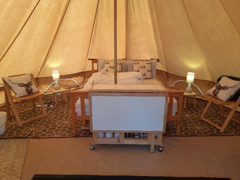 a tent with a table and two lights in it at Glamping Bell Tent in Norton Saint Philip