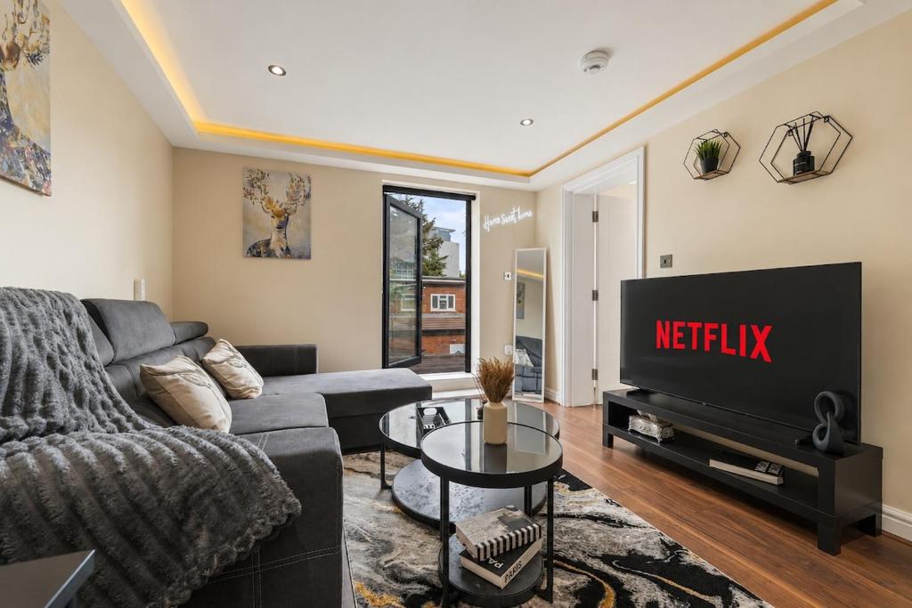 a living room with a couch and a tv at Premium Apartment Steps from Wembley Park in London