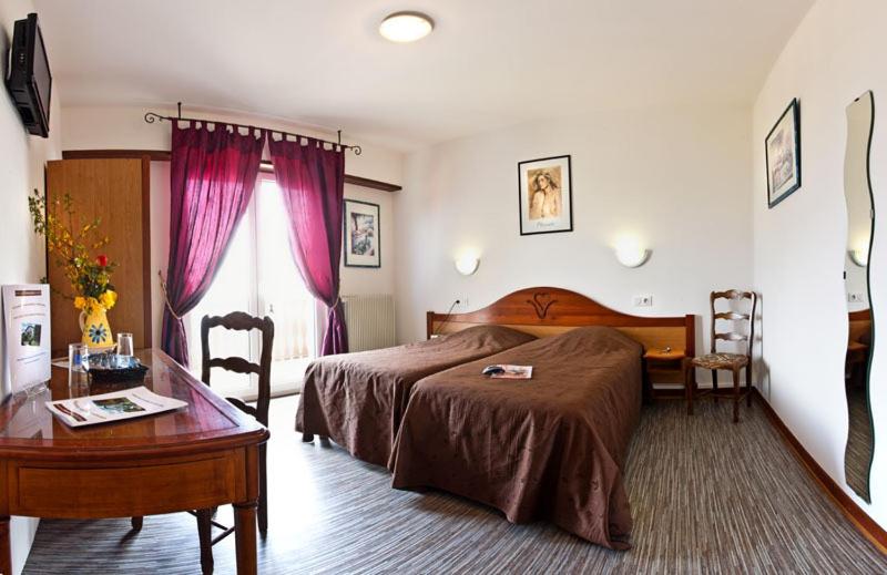 a bedroom with a bed and a desk and a table at Auberge Obersolberg in Eschbach-au-Val