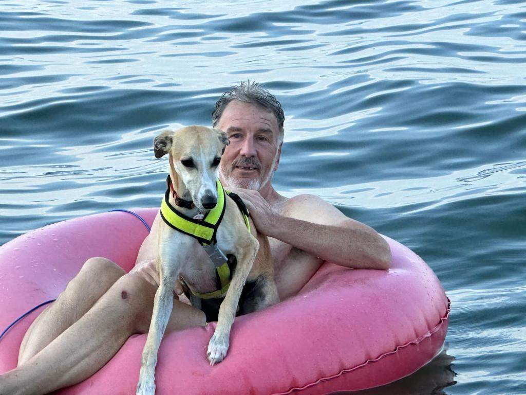 a man and a dog on a pink raft in the water at Lovely Lakeside Lodge in Canandaigua